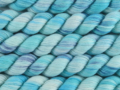 A close up of variegated aqua and white with hints of navy blue mini skeins of superwash merino and nylon 4ply fingering sock yarn arranged horizontally (Tiffany Blues on Tough Stocking Mini)