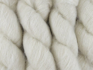 A close up of natural warm white coloured skeins of superfine kid mohair and silk 2ply lace yarn (Undyed on Kid Glove Lace)