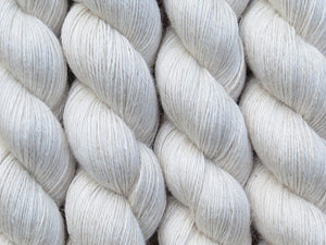 A close up of warm oatmeal white coloured skeins of non-superwash baby alpaca, silk and linen 4ply fingering weight yarn (Undyed on Spinifex)