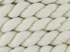 A close up of multiple undyed natural warm white mini skeins of superwash merino and nylon 4ply fingering sock yarn arranged horizontally (Undyed on Tough Stocking Mini)