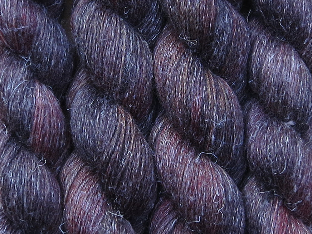 A close up of variegated brown with hints of black, red and golden yellow coloured skeins of non-superwash baby alpaca, silk and linen 4ply fingering weight yarn (Vegemite on Spinifex)
