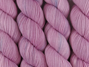 A close up of semi-solid dusty pink coloured skeins of superwash merino and nylon 4ply fingering sock yarn (Vintage Rose on Tough Stocking)